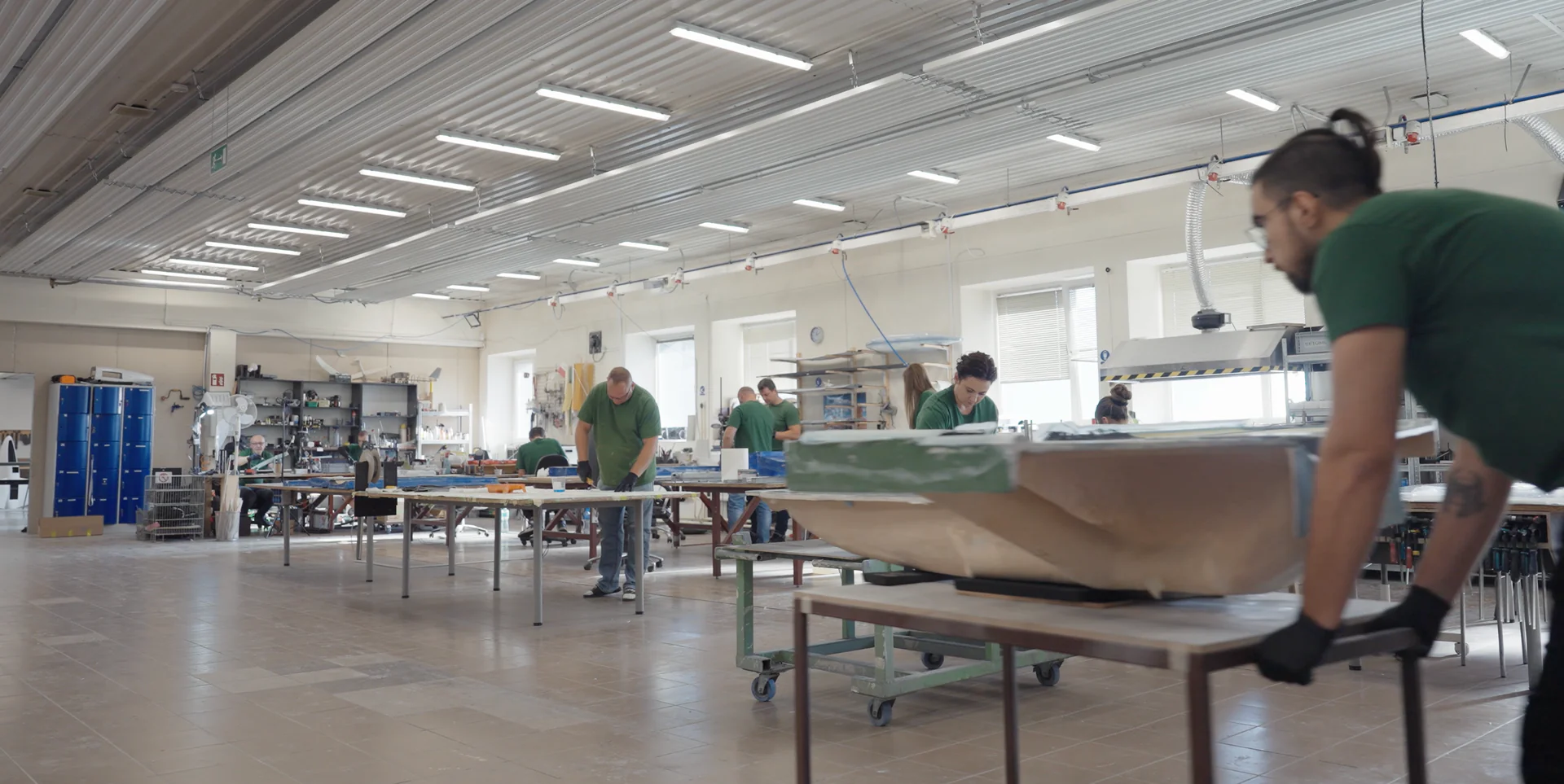Pracownik hali produkcyjnej przenosi element kompozytowy płatowca